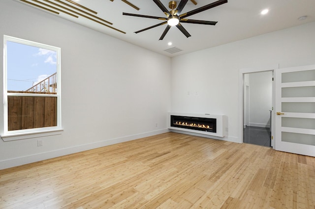 unfurnished living room featuring ceiling fan and light hardwood / wood-style flooring