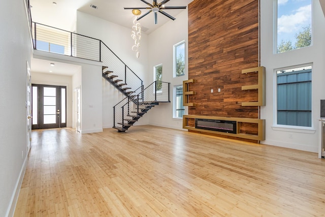 unfurnished living room with high vaulted ceiling, light hardwood / wood-style floors, and ceiling fan