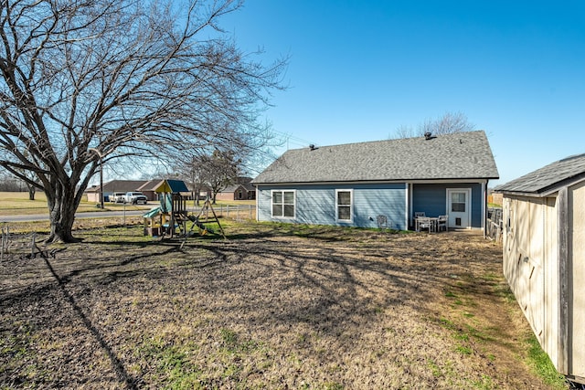 rear view of house featuring a playground and a lawn