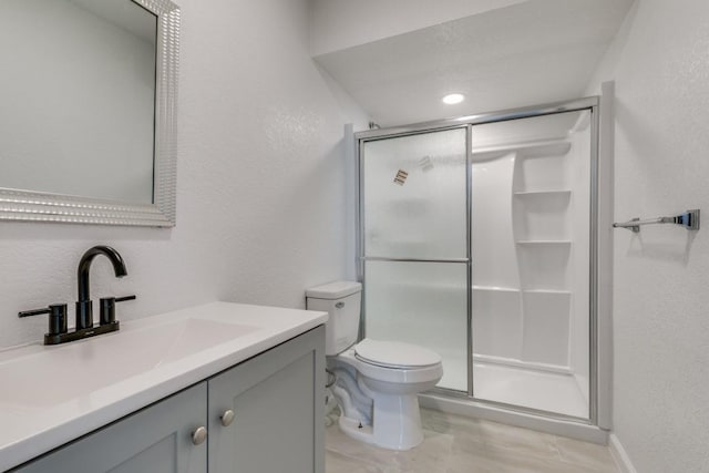 bathroom featuring a shower with shower door, toilet, and vanity