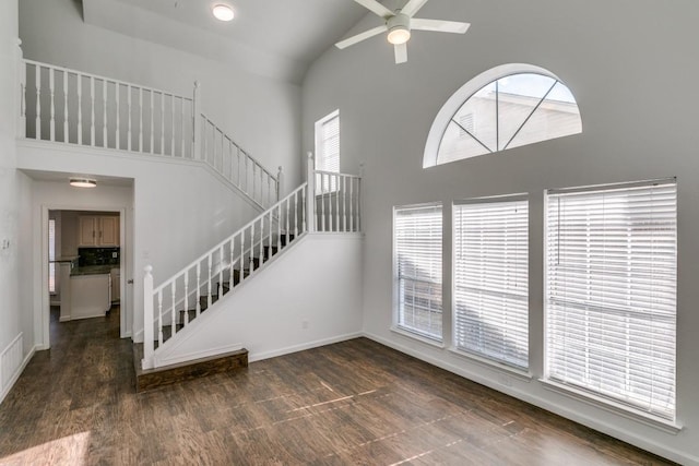 unfurnished living room with ceiling fan, dark wood-type flooring, and high vaulted ceiling