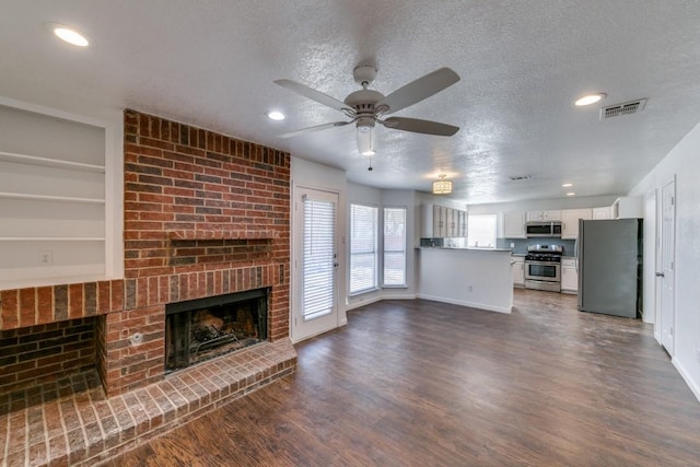 unfurnished living room with a textured ceiling, ceiling fan, a fireplace, and built in shelves