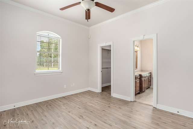 unfurnished bedroom with a spacious closet, ensuite bath, a closet, light wood-type flooring, and ceiling fan