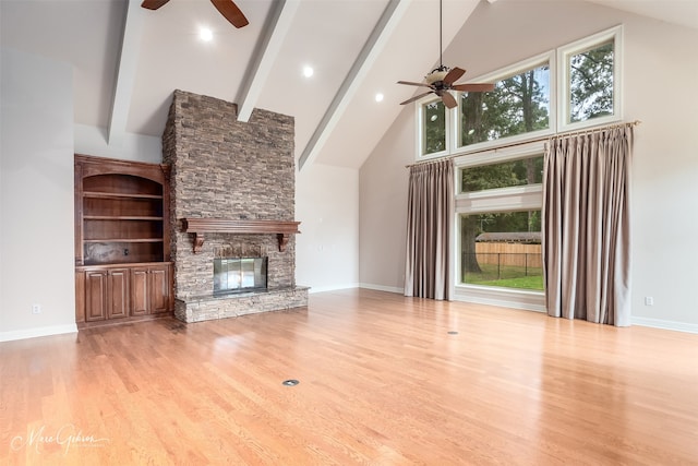 unfurnished living room featuring ceiling fan, a fireplace, high vaulted ceiling, light hardwood / wood-style flooring, and beamed ceiling