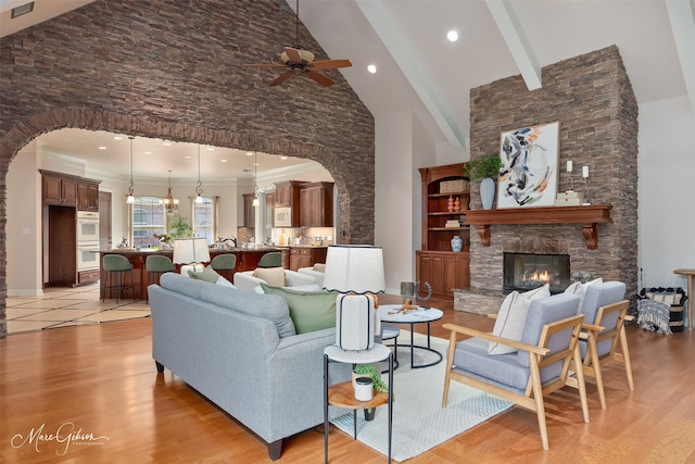 9356 Dogwood Trl, Haughton, LA 71037 - living area featuring ceiling fan with notable chandelier, arched walkways, light wood-style floors, and high vaulted ceiling