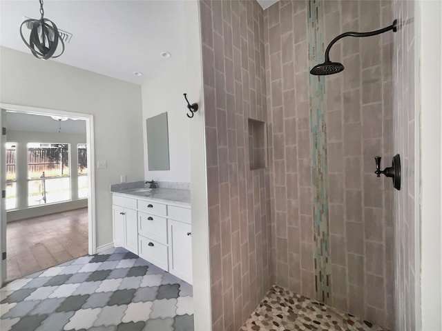 bathroom with tiled shower and vanity