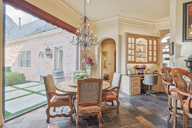 dining space with ornamental molding, arched walkways, a chandelier, and stone tile floors