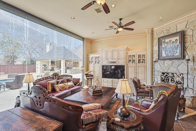 living room with crown molding and a stone fireplace