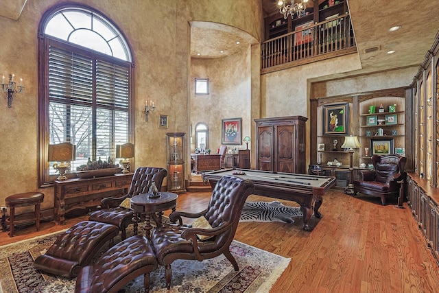 rec room with hardwood / wood-style flooring, pool table, built in features, and a high ceiling