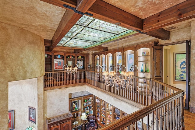 stairs featuring a high ceiling, beamed ceiling, coffered ceiling, and wood finished floors