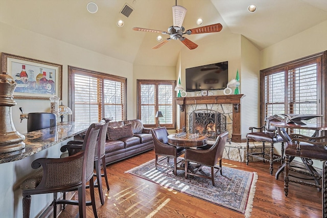 living room featuring ceiling fan, dark hardwood / wood-style flooring, high vaulted ceiling, and a fireplace