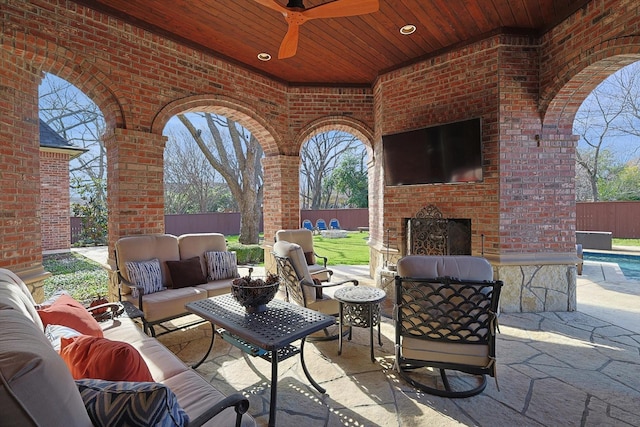 view of patio / terrace with ceiling fan and an outdoor living space with a fireplace