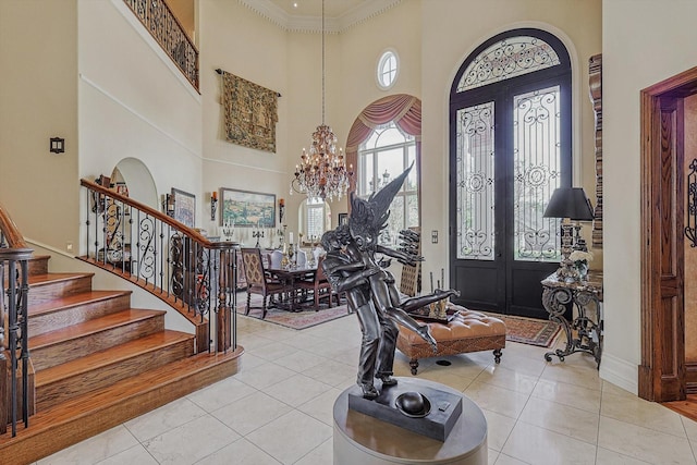 tiled entryway with ornamental molding, stairway, a towering ceiling, and an inviting chandelier