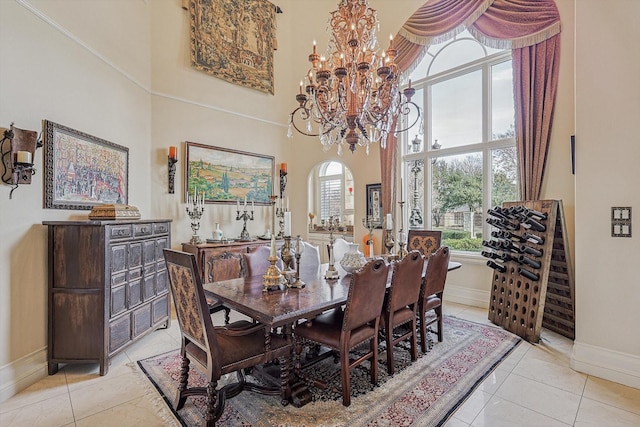 dining area with light tile patterned floors, arched walkways, a towering ceiling, and an inviting chandelier