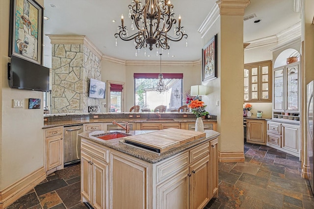 kitchen with kitchen peninsula, sink, light brown cabinets, and a center island with sink