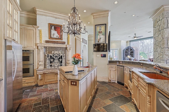 kitchen with stainless steel appliances, a sink, stone tile flooring, and crown molding