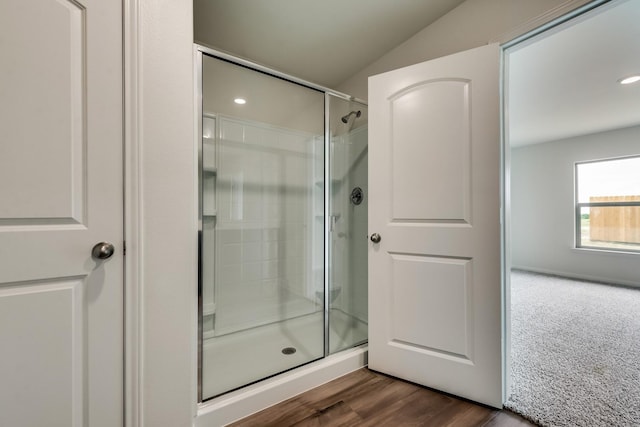 bathroom with lofted ceiling, hardwood / wood-style floors, and a shower with door