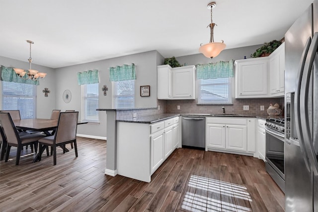 kitchen featuring white cabinets, dark hardwood / wood-style flooring, stainless steel appliances, hanging light fixtures, and kitchen peninsula