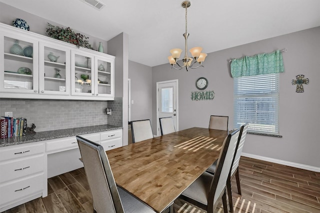 dining room with dark wood-type flooring and a notable chandelier