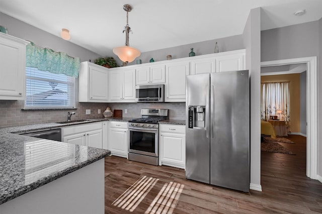 kitchen featuring hanging light fixtures, sink, stainless steel appliances, and white cabinetry