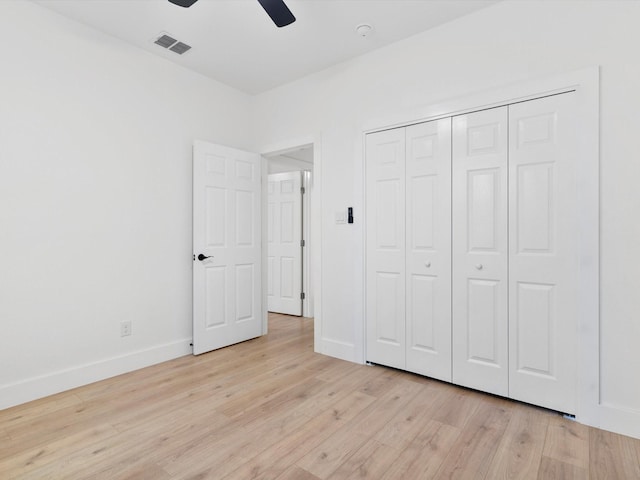 unfurnished bedroom with light wood-type flooring, baseboards, visible vents, and a closet