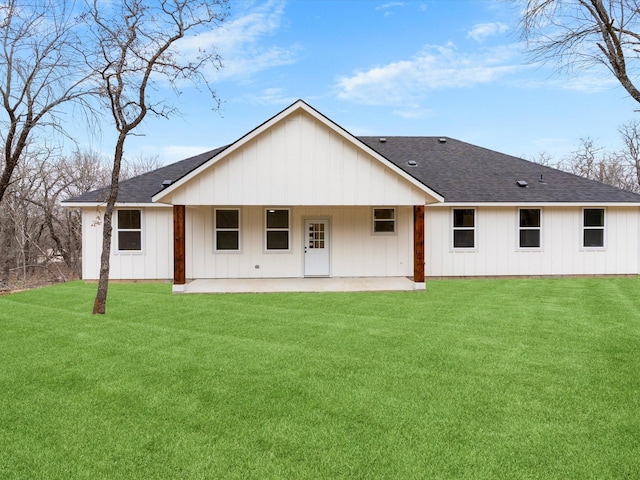 back of house with roof with shingles, a lawn, a patio area, and board and batten siding