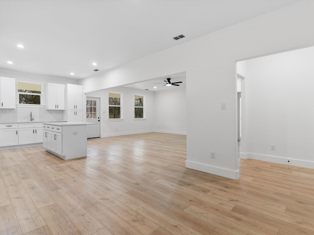 unfurnished living room featuring light wood finished floors, a sink, and recessed lighting