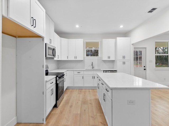 kitchen featuring a sink, a center island, electric stove, decorative backsplash, and stainless steel microwave