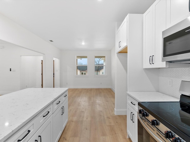 kitchen featuring decorative backsplash, appliances with stainless steel finishes, light wood-style floors, white cabinets, and light stone countertops