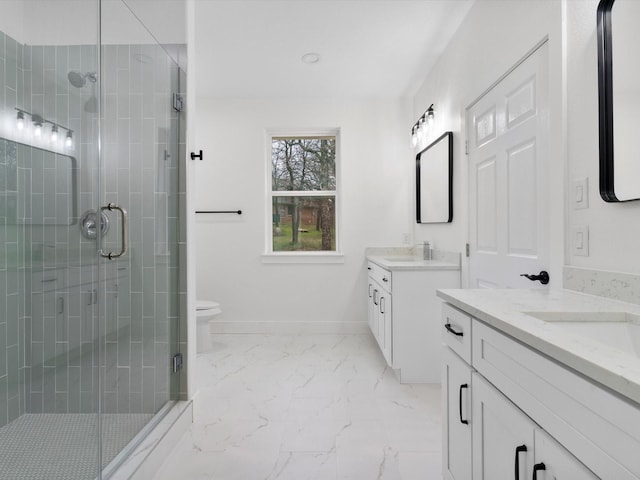 full bathroom featuring marble finish floor, two vanities, a stall shower, a sink, and baseboards