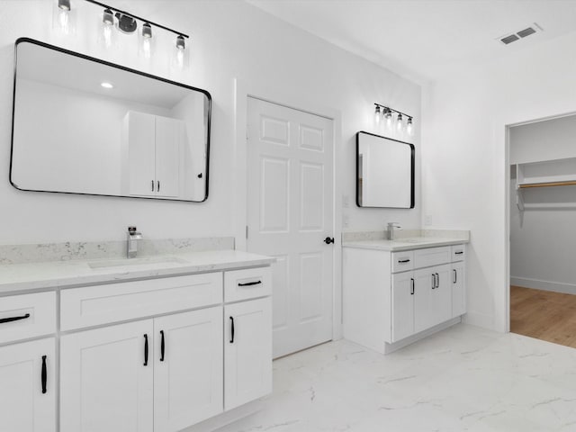 full bath featuring marble finish floor, visible vents, two vanities, and a sink