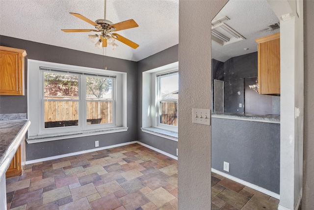 unfurnished dining area with ceiling fan and a textured ceiling