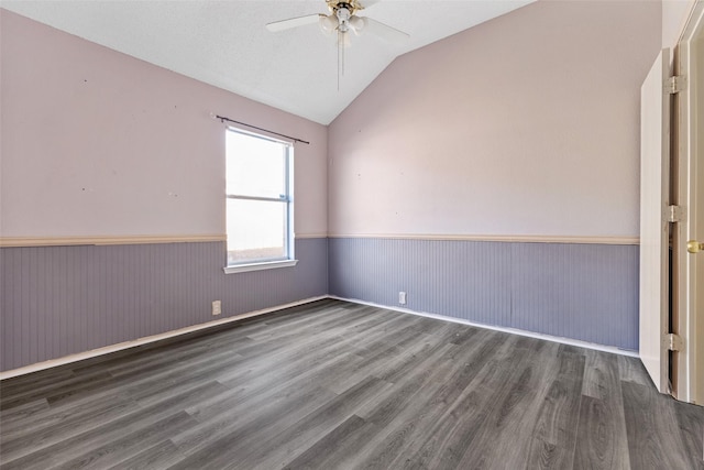 spare room with ceiling fan, vaulted ceiling, and dark wood-type flooring