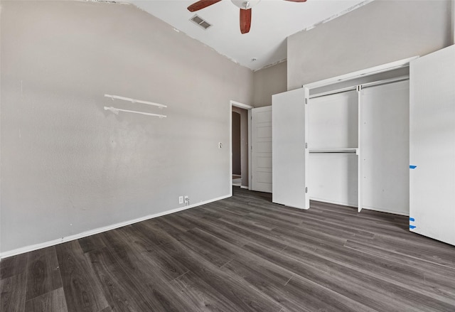 unfurnished bedroom featuring dark wood-type flooring, ceiling fan, a closet, and a towering ceiling