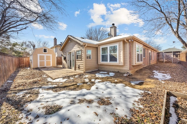 snow covered property with a storage shed and a patio