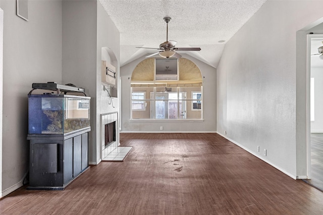 unfurnished living room featuring vaulted ceiling, ceiling fan, dark hardwood / wood-style flooring, and a tiled fireplace