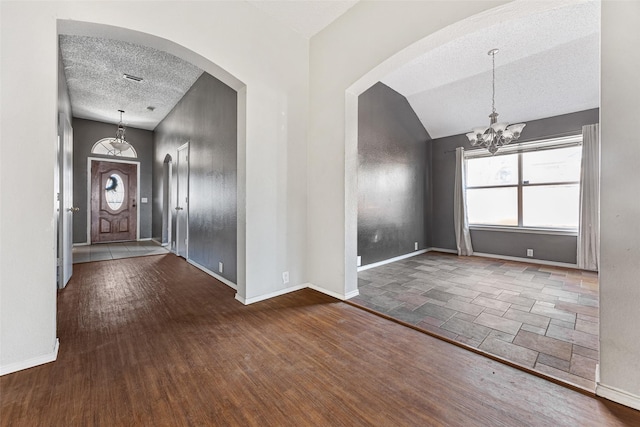 entryway with lofted ceiling, dark hardwood / wood-style flooring, an inviting chandelier, and a textured ceiling