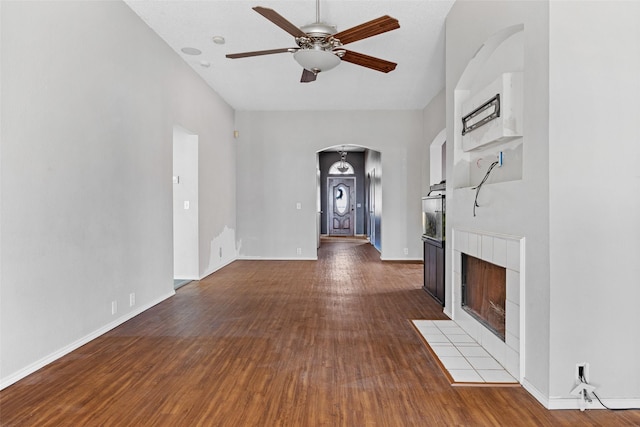 unfurnished living room with ceiling fan, wood-type flooring, and a tile fireplace