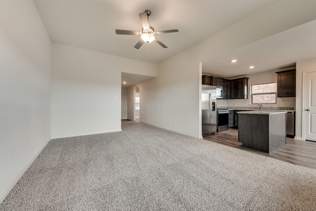 kitchen with carpet floors, ceiling fan, a center island, appliances with stainless steel finishes, and dark brown cabinets