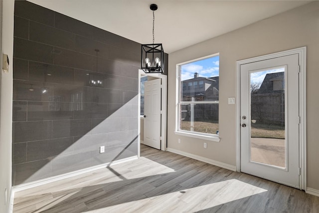 unfurnished dining area with a healthy amount of sunlight, a chandelier, and light hardwood / wood-style flooring