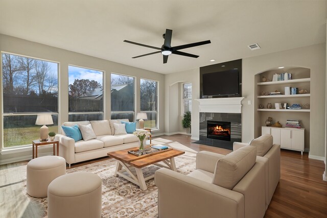 unfurnished living room with ceiling fan, hardwood / wood-style flooring, and a tile fireplace