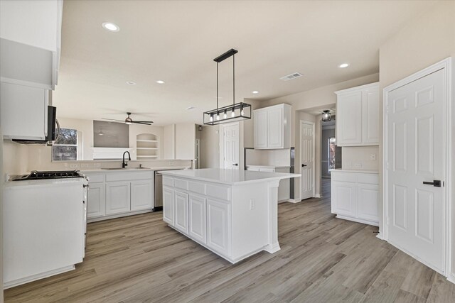 kitchen with light hardwood / wood-style floors, a kitchen island, sink, white cabinetry, and hanging light fixtures