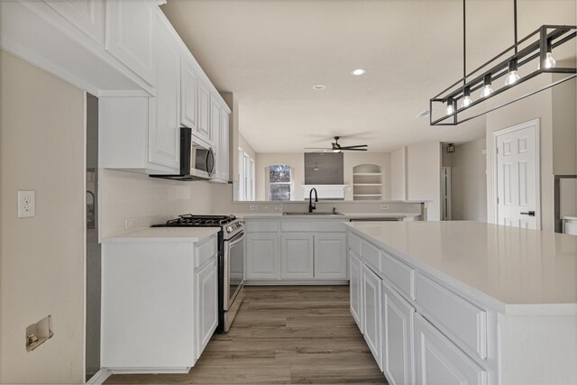 kitchen with a kitchen island, sink, white cabinetry, hanging light fixtures, and appliances with stainless steel finishes