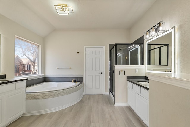 bathroom featuring lofted ceiling, wood-type flooring, separate shower and tub, and vanity