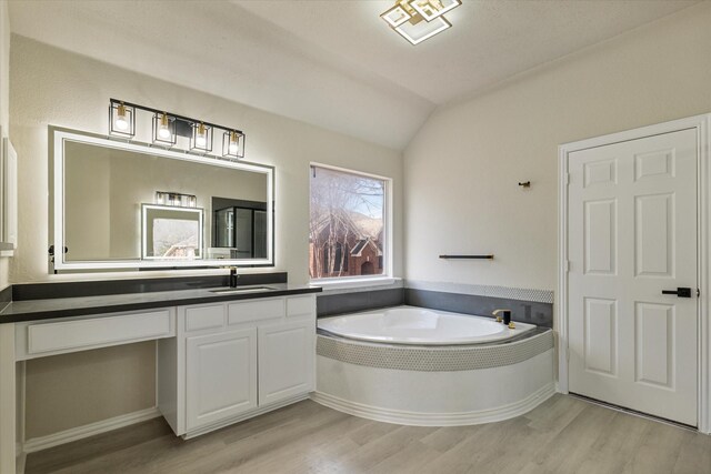 bathroom featuring hardwood / wood-style floors, a bathtub, vanity, and vaulted ceiling