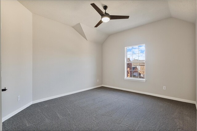 empty room with vaulted ceiling, ceiling fan, and dark colored carpet