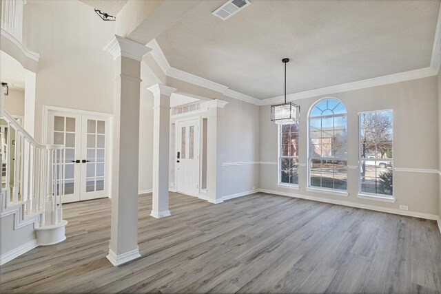 foyer with decorative columns, wood-type flooring, crown molding, and a notable chandelier