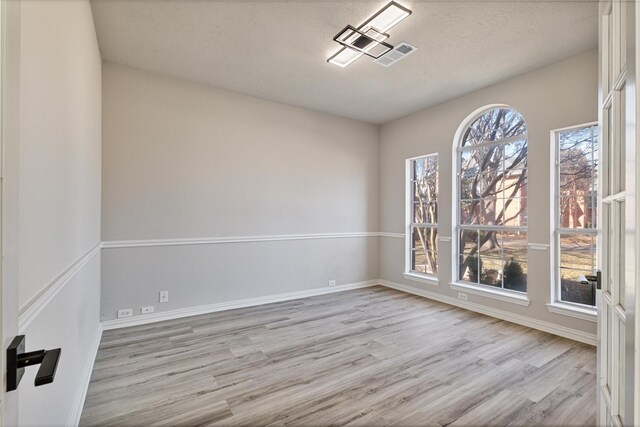 unfurnished dining area featuring light wood-type flooring, a chandelier, crown molding, and french doors