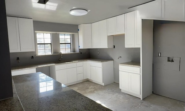 kitchen featuring sink, stone counters, and white cabinetry