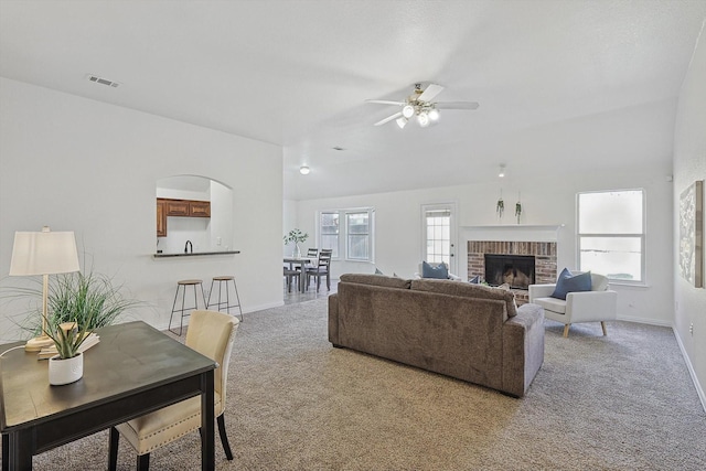 carpeted living room with ceiling fan and a brick fireplace